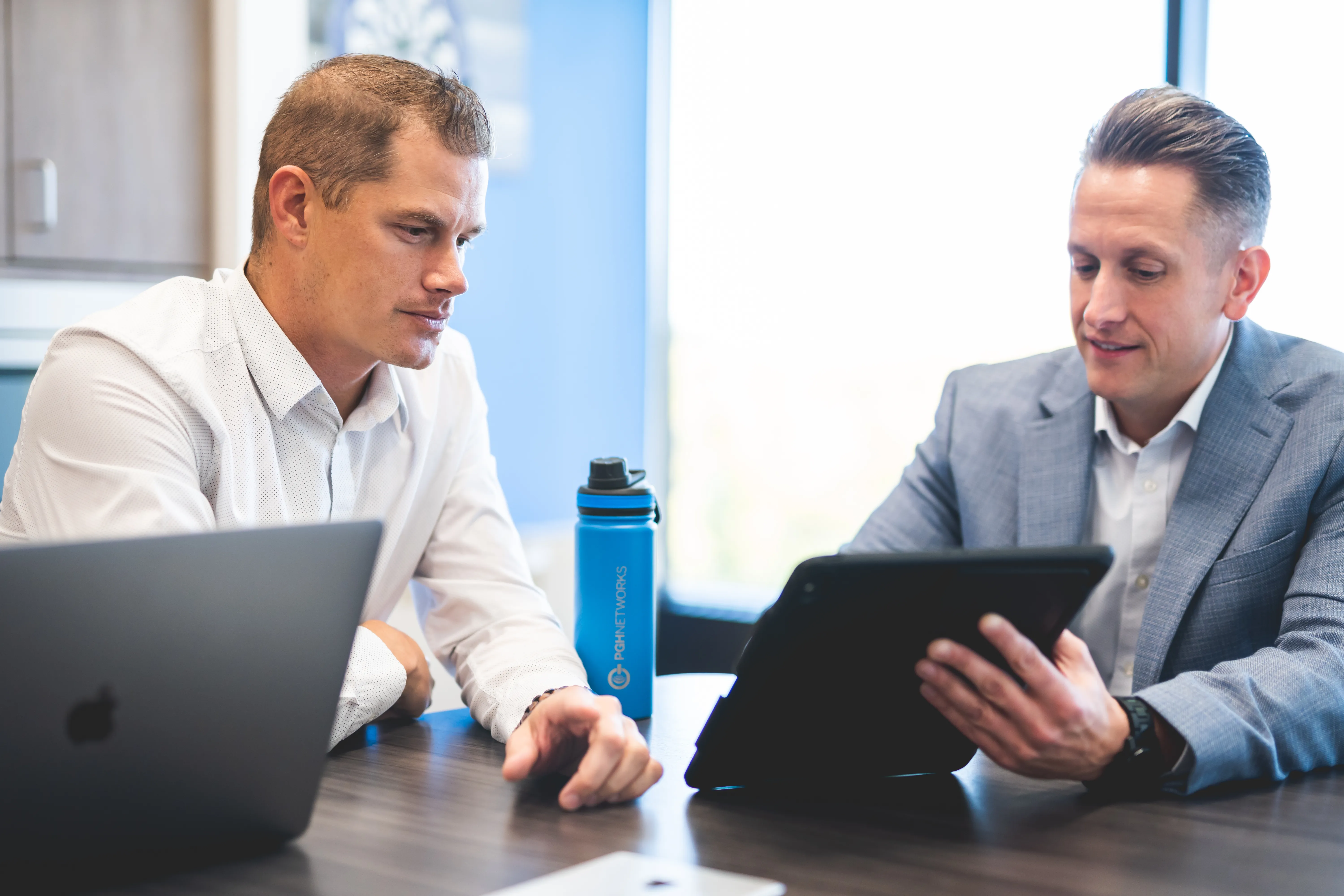 A PGH Networks consultant reviewing plans on a tablet with a client.
